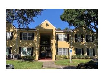 Inviting yellow two-story condo with black shutters and well-maintained landscaping at 2013 Dixie Belle Dr # 2013K, Orlando, FL 32812