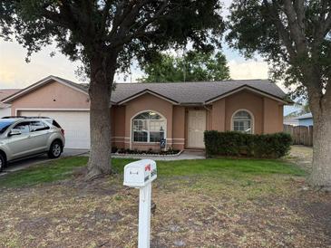 Charming single-story home featuring a well-manicured lawn, attached garage, and mature trees shading the front at 6616 Shepherd Oaks St, Lakeland, FL 33811