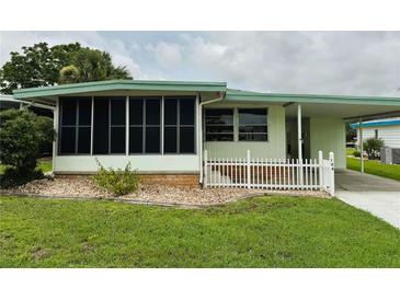 Charming light green home with screened porch and adjacent carport at 106 Azalea Trl, Leesburg, FL 34748