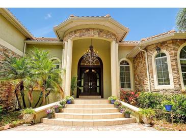 Stately home entrance with stone accents, double doors, chandelier, and manicured landscaping at 1502 Hempel Ave, Windermere, FL 34786