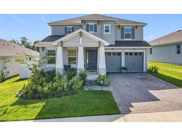Charming two-story home with a welcoming front porch, landscaped yard, and two-car garage at 2044 Keystone Pass Blvd, Minneola, FL 34715