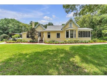 Charming yellow home with a manicured lawn and inviting front porch, perfect for relaxing outdoors at 3450 Ohio Ave, Sanford, FL 32773