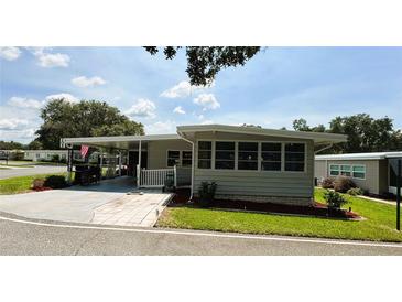 Charming single-story home with a carport and manicured lawn under a sunny sky at 103 Poinsettia Cv, Leesburg, FL 34748