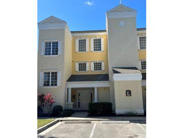 Charming condo featuring a yellow facade, shuttered windows, and a welcoming entrance at 1310 Seven Eagles Ct # 102, Reunion, FL 34747