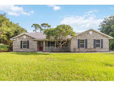 Charming single-story home with a brick facade, red door, covered porch, and lush green lawn at 1330 Englewood Dr, St Cloud, FL 34772