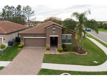 Beautiful single-story home features a brick paver driveway and manicured lawn with a palm tree at 4004 Prima Lago Cir, Lakeland, FL 33810