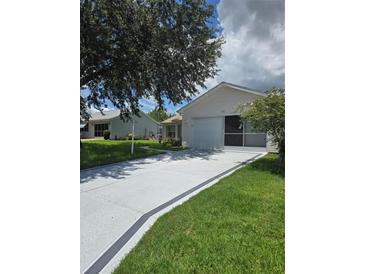 Charming single-story home with a manicured lawn, long driveway, and a screened-in garage at 527 San Pedro Dr, The Villages, FL 32159