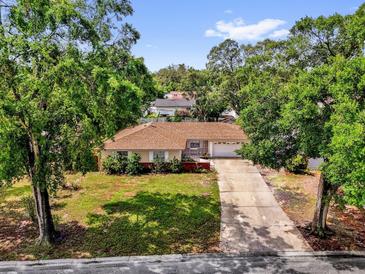 Charming single-story home with a well-manicured lawn and mature trees lining the property at 5806 Fernhill Dr, Orlando, FL 32808