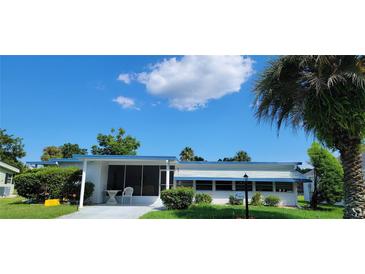 Charming single-story home with blue and white trim, lush landscaping, and a screened front patio at 804 Maple Ln, Lady Lake, FL 32159