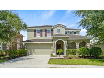 Two-story house with a green exterior, attached garage, and manicured landscaping at 5144 Oakbourne Ave, Davenport, FL 33837