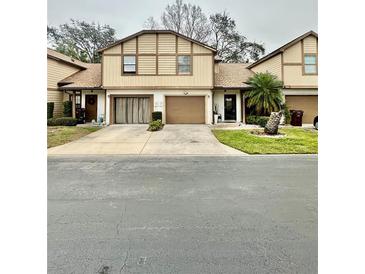 Tan two-story townhouse with brown garage doors and landscaping at 2031 Balboa Way, Kissimmee, FL 34741