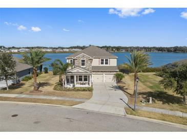 Two-story home with lake view, stone exterior, and palm trees at 507 Natural Bridge Ct, Apopka, FL 32703