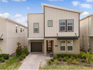 Modern two-story home featuring a brick driveway, an attached garage, and well-maintained landscaping at 4348 Quote St, Kissimmee, FL 34746