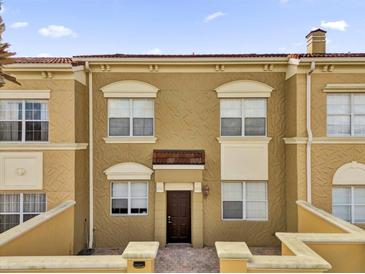 Townhouse with light brown stucco, red-tiled roof, white window frames, and covered entryway at 2774 Bella Vista Dr, Davenport, FL 33897