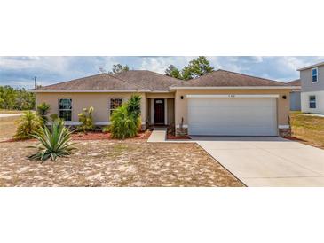 Tan one-story house with a two-car garage and landscaping at 340 Elderberry Ct, Kissimmee, FL 34759
