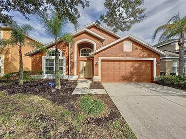 Charming single-story home features a 2-car garage and a well-manicured front yard with palm trees at 1058 Orange Cosmos Blvd, Davenport, FL 33837