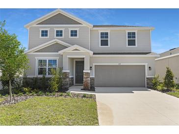 Charming two-story home featuring a manicured lawn, stone accents, and a two-car garage at 1635 Sugarbelle Cir, Mascotte, FL 34753