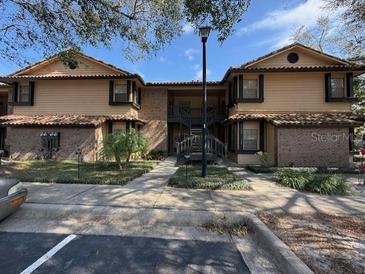 Attractive condominium complex with manicured landscaping, covered entry, and terra cotta tile roofing at 300 New Waterford Pl # 204, Longwood, FL 32779