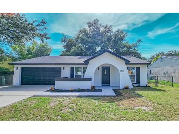 Charming single-story home featuring an arched entryway, manicured lawn, and attached two-car garage at 2220 Crystal Grove Ln, Lakeland, FL 33801