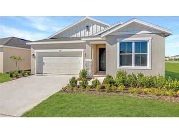 One-story home with neutral siding, landscaping, and a two-car garage at 930 Heirloom Dr, Haines City, FL 33844