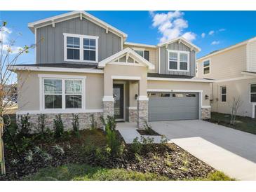Two-story house with gray siding, stone accents, and a two-car garage at 883 Griffon Ave, Lake Alfred, FL 33850