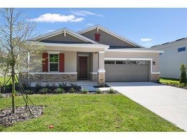 Beautiful single Gathering home with well-manicured lawn and neutral toned exterior with red shutters, stone accents and attached garage at 4220 Sawtooth Ct, Tavares, FL 32778