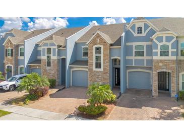 Attractive townhome with two-car garage, stone accents, and well manicured landscaping at 2106 Chatham Place Dr, Orlando, FL 32824
