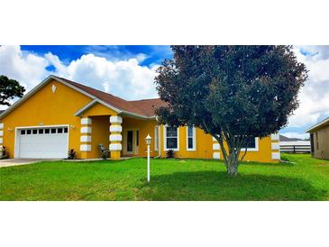 Charming yellow single-story home featuring a well-manicured lawn and a two-car garage at 9549 Sw 53Rd Cir, Ocala, FL 34476
