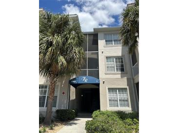 A condo building with a blue awning and palm trees in front of the building at 3301 Whitestone Cir # 308, Kissimmee, FL 34741