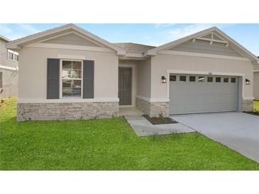Newly constructed home with gray siding, stone accents, and a two-car garage at 4212 Sawtooth Ct, Tavares, FL 32778