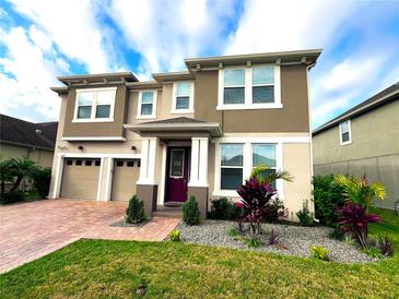 Two-story home with a two-car garage, red brick drive, and manicured landscaping at 8118 Platts Ave, Orlando, FL 32832