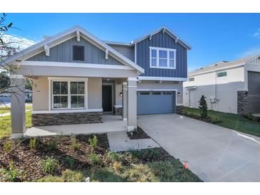 Two-story house with gray siding, stone accents, and a two-car garage at 4200 Sawtooth Ct, Tavares, FL 32778