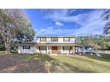 Two-story house with white siding, brown double doors, and a landscaped lawn at 32122 Hickory Ln, Sorrento, FL 32776