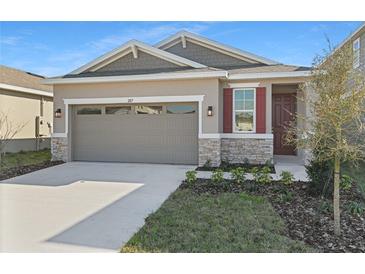 Charming home featuring stone accents, a two-car garage, and a well-manicured lawn at 207 Bull Frog Ln, Umatilla, FL 32784