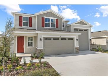Charming two-story home with a two car garage, red shutters, landscaped yard, and a welcoming red front door at 2111 Riely Ave, Eagle Lake, FL 33839
