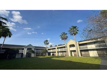 A charming building featuring a grassy courtyard and palm trees against a clear blue sky at 5245 W Irlo Bronson Memorial Hwy # 244, Kissimmee, FL 34746