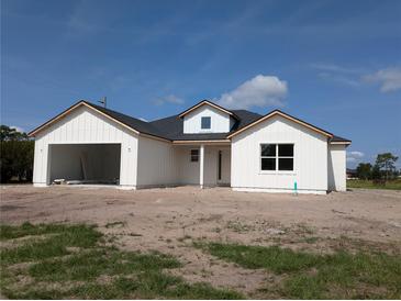 New construction shows a charming white home with an attached garage, and a dormer window detail at 3664 Cord Ave, St Cloud, FL 34772