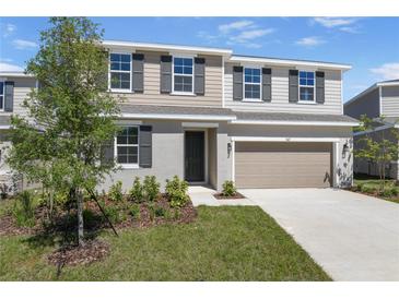 Charming two-story home with a manicured lawn, neutral color palette, and an attached two-car garage at 1667 Sugarbelle Cir, Mascotte, FL 34753