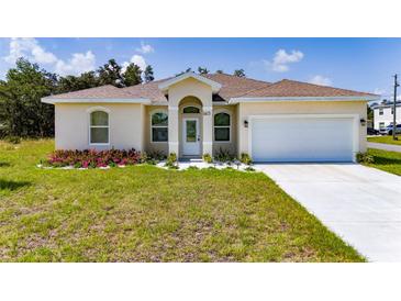Charming single-story home with a well-manicured lawn, landscaped flower bed, and attached two-car garage at 1415 Orlando Way, Kissimmee, FL 34759