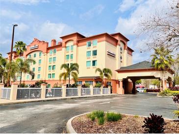 Inviting hotel exterior with covered entrance, manicured landscaping and ample parking on a partly cloudy day at 3000 Maingate Ln # 412, Kissimmee, FL 34747