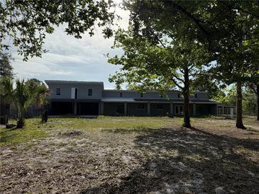 Exterior view of the two-story home with large yard and mature trees at 2728 Adair Rd, Davenport, FL 33837