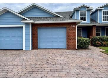 Charming blue townhome with brick accents, two-car garage and paved driveway at 3480 Home Town Ln, Saint Cloud, FL 34769