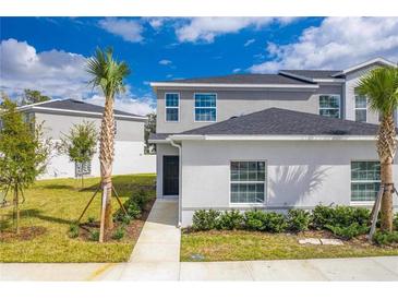 Two-story townhome with gray exterior, landscaping, and walkway at 2023 Claudia Ln, Kissimmee, FL 34741