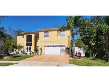 Two-story home with a two-car garage, lush landscaping, and a screened in front porch, creating a charming curb appeal at 2606 Royal Fern Pl, Kissimmee, FL 34758