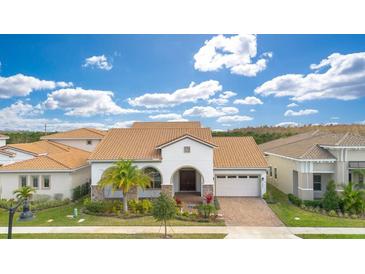 Charming single-Gathering home featuring a red-tiled roof, arched entryway, two-car garage, and lush landscaping at 13809 Abberwick Dr, Orlando, FL 32832