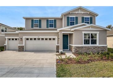 Charming two-story home features a two-car garage, teal shutters and door, and stone accents at 1488 August Gray Dr, Kissimmee, FL 34744