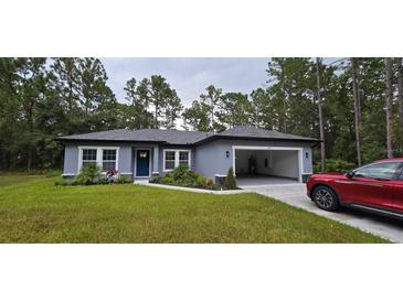 Newly built home with a gray exterior, two-car garage, and landscaped front yard at 6817 Sw 131St Pl, Ocala, FL 34473