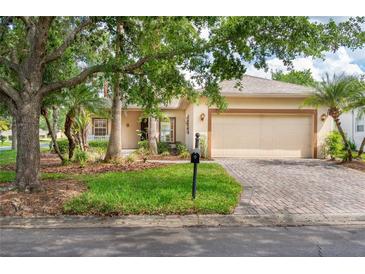 Charming single-story home with a well-manicured lawn, mature trees, and a brick driveway leading to an attached two-car garage at 753 Largo Pass, Poinciana, FL 34759