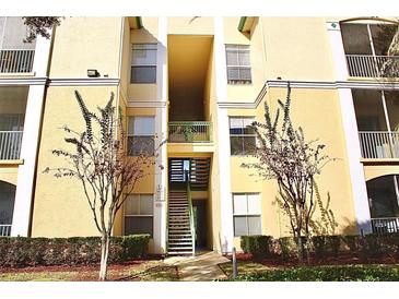 Exterior of tan colored building with outdoor staircase and pedestrian access to upper floors at 8830 Dunes Ct # 12 207, Kissimmee, FL 34747