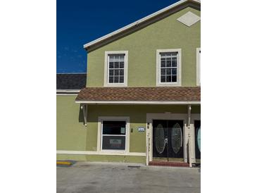 A two-story green home with a brown shingle roof and a bright blue sky above at 1069 Universal Rest Pl, Kissimmee, FL 34744